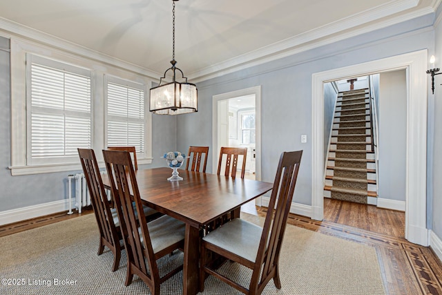 dining space featuring light wood-type flooring, stairway, a notable chandelier, and crown molding