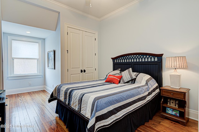 bedroom with hardwood / wood-style flooring, baseboards, a closet, and ornamental molding