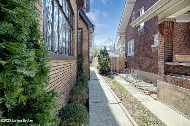 view of side of property with a gate and brick siding