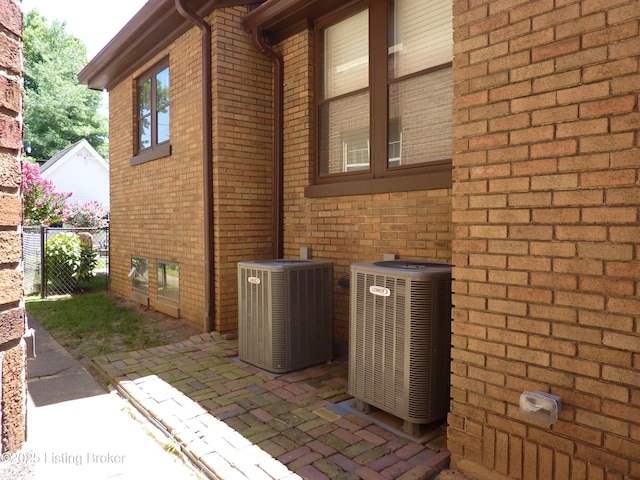 exterior space featuring central air condition unit, a patio, brick siding, and fence