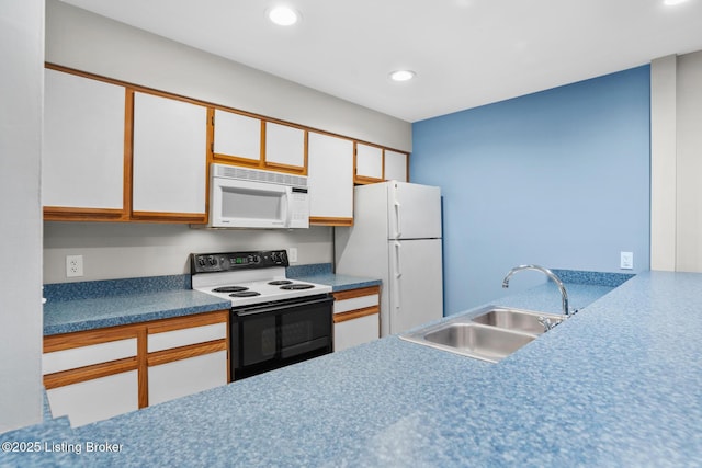 kitchen with recessed lighting, white appliances, white cabinetry, and a sink