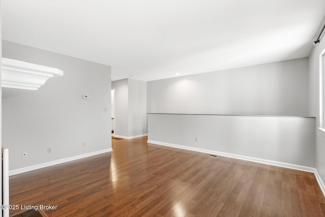 spare room featuring baseboards and wood finished floors