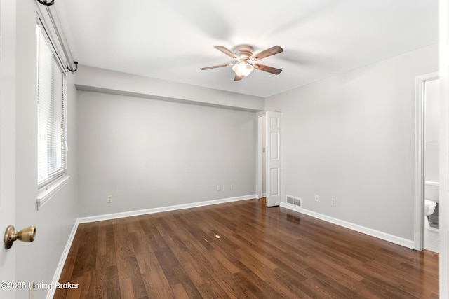 empty room featuring visible vents, baseboards, a ceiling fan, and dark wood-style flooring