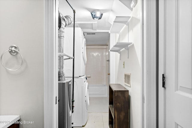 walk in closet featuring stacked washer and dryer, light tile patterned flooring, and visible vents