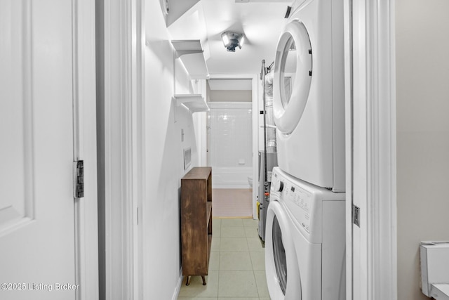 washroom with stacked washer and clothes dryer, light tile patterned flooring, and laundry area