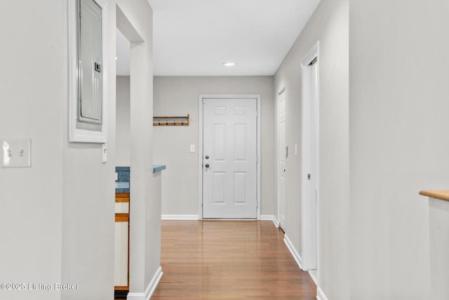 hall with electric panel, wood finished floors, and baseboards