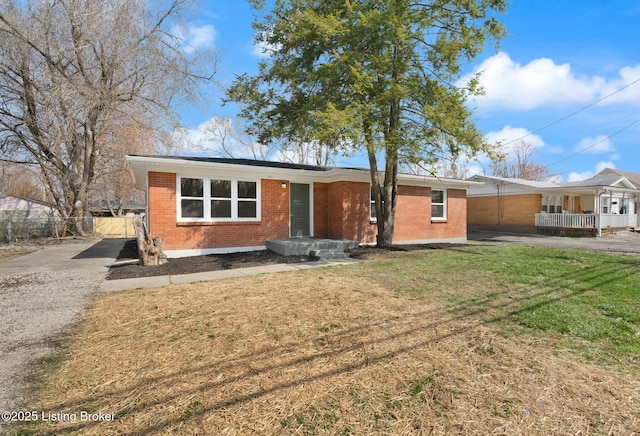 single story home with driveway, fence, a front yard, a carport, and brick siding