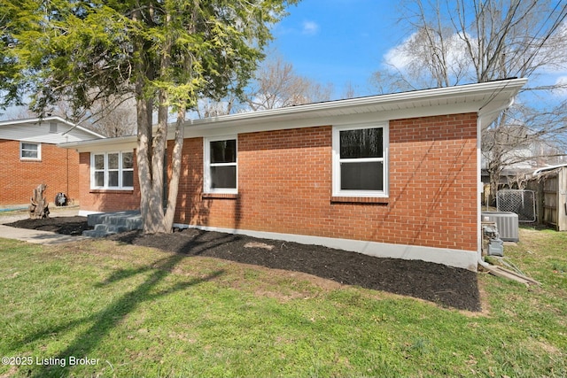 back of house with fence, a lawn, brick siding, and central AC