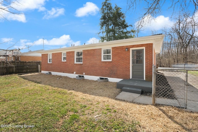 rear view of property featuring brick siding, a lawn, and fence