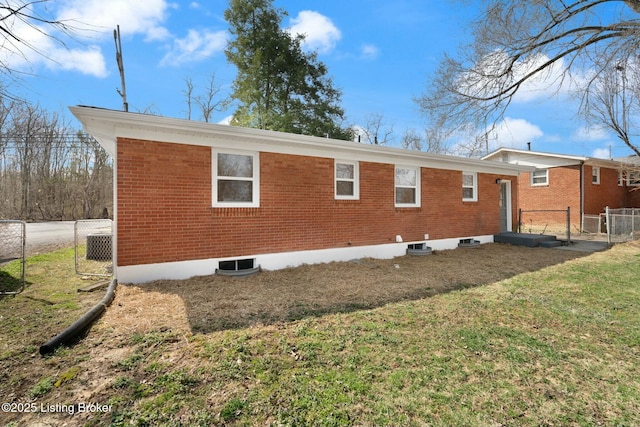 view of property exterior featuring a gate, a yard, brick siding, and fence