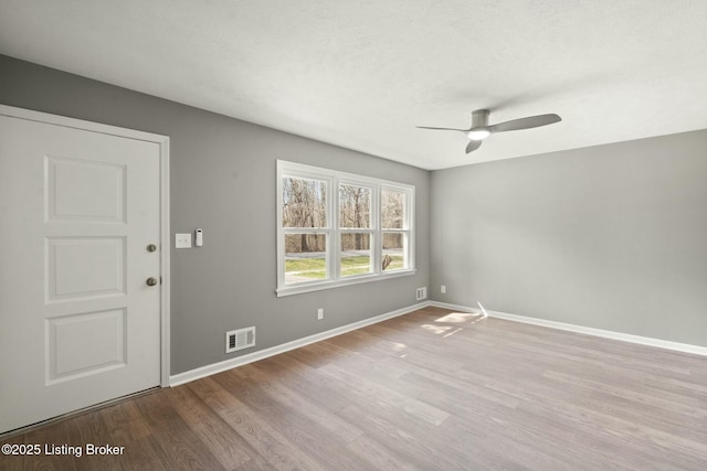 unfurnished room with wood finished floors, a ceiling fan, visible vents, baseboards, and a textured ceiling