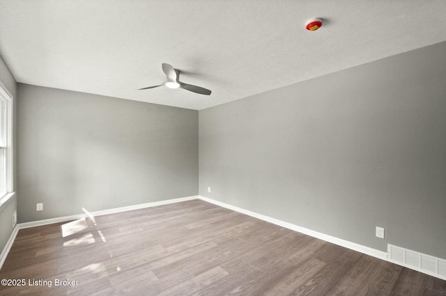 spare room with visible vents, baseboards, a ceiling fan, and wood finished floors