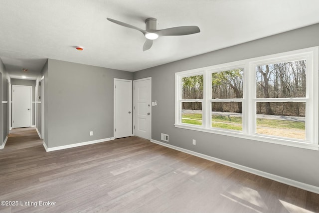 unfurnished room featuring visible vents, a ceiling fan, baseboards, and wood finished floors