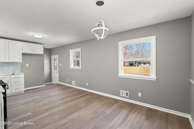 unfurnished dining area with visible vents, baseboards, and light wood-style flooring