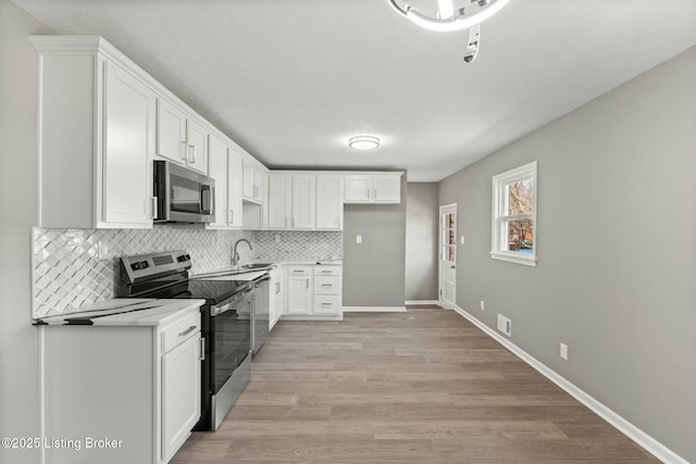 kitchen featuring tasteful backsplash, visible vents, light wood finished floors, stainless steel appliances, and a sink