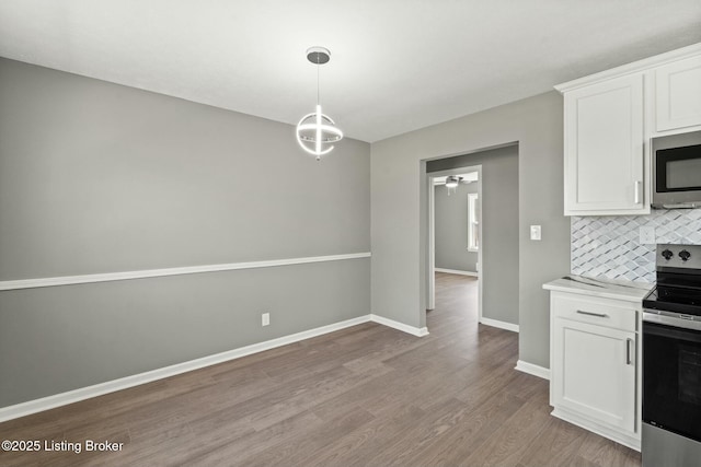 kitchen featuring wood finished floors, stainless steel appliances, decorative backsplash, light countertops, and white cabinets