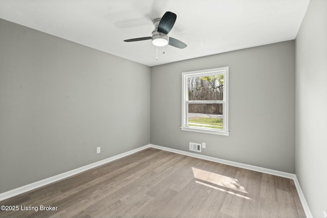 empty room featuring visible vents, ceiling fan, baseboards, and wood finished floors