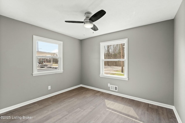 unfurnished room with visible vents, ceiling fan, baseboards, and wood finished floors