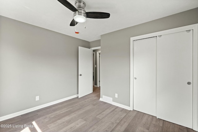 unfurnished bedroom with a closet, a ceiling fan, baseboards, and wood finished floors