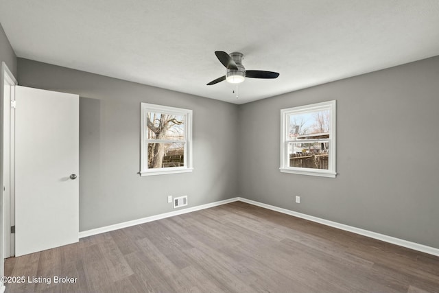 unfurnished room with visible vents, baseboards, wood finished floors, and a ceiling fan