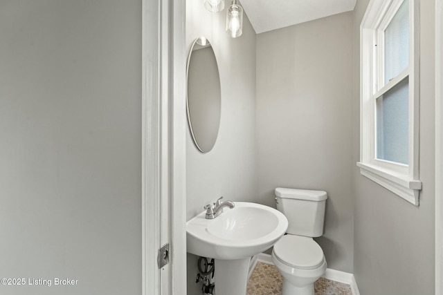 half bathroom featuring toilet, baseboards, and a sink