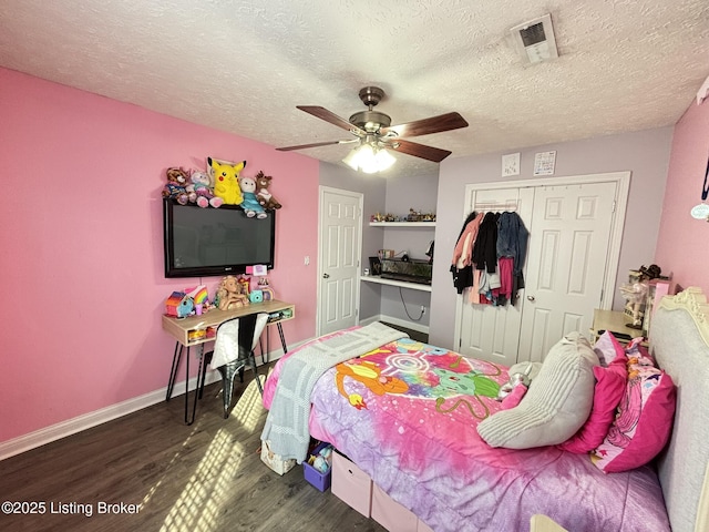 bedroom with wood finished floors, visible vents, baseboards, ceiling fan, and a closet