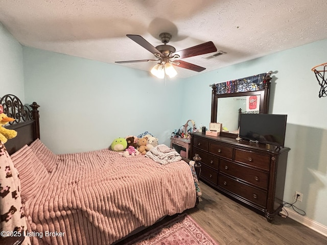 bedroom with ceiling fan, wood finished floors, visible vents, and a textured ceiling