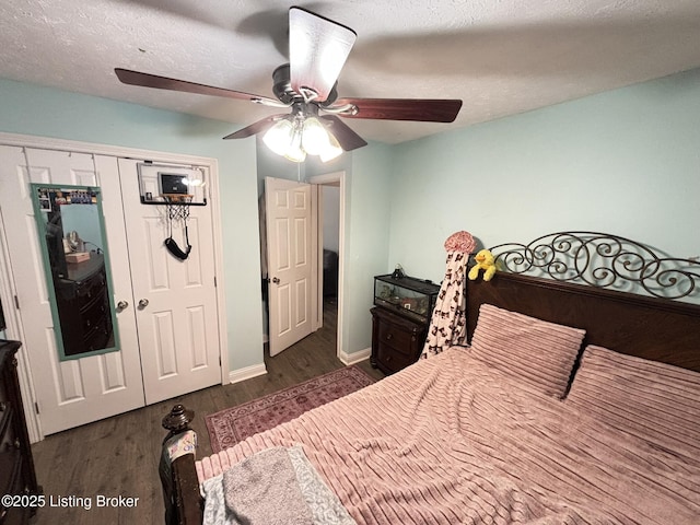 bedroom featuring a textured ceiling, dark wood-style floors, a closet, baseboards, and ceiling fan