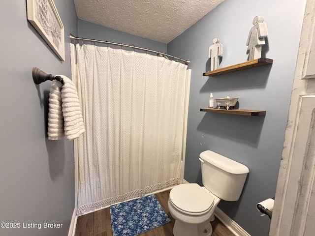 bathroom featuring a shower with curtain, toilet, wood finished floors, and a textured ceiling