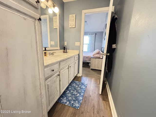 bathroom featuring baseboards, wood finished floors, ensuite bath, and vanity