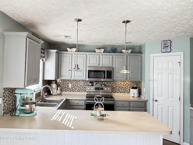 kitchen with gray cabinetry, stainless steel appliances, and a sink