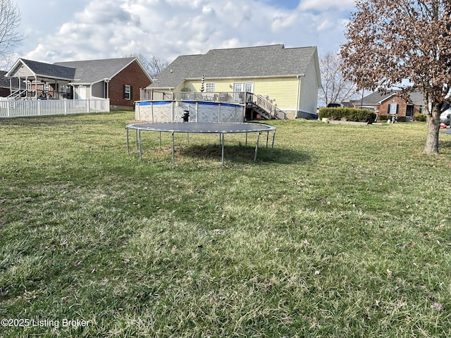 view of yard with a trampoline, fence, and an outdoor pool