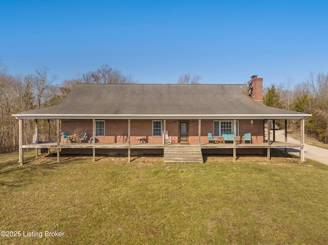 back of property with brick siding, a wooden deck, a yard, and a chimney