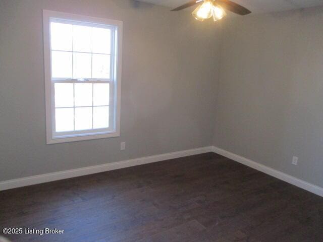 spare room with baseboards, dark wood-type flooring, and a ceiling fan