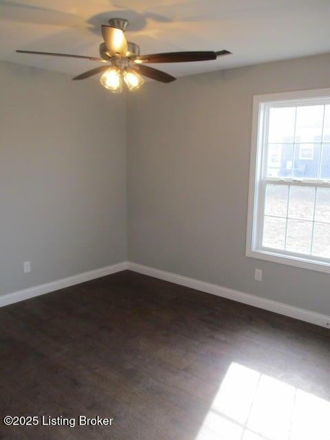 empty room featuring baseboards, dark wood-style floors, and a ceiling fan