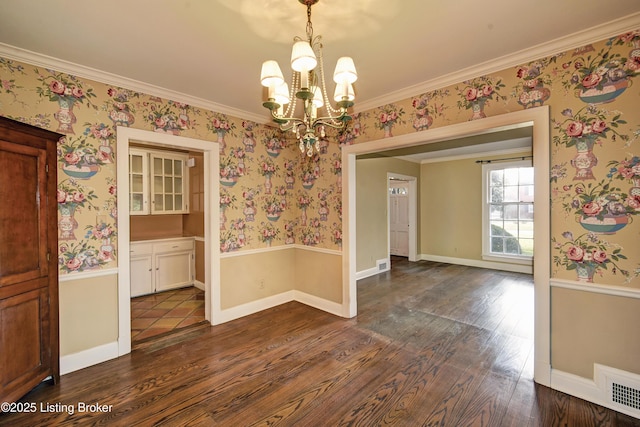 unfurnished dining area with wallpapered walls, a notable chandelier, dark wood finished floors, and visible vents