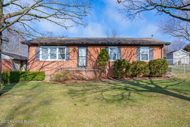 view of front of property with brick siding, a front lawn, and fence