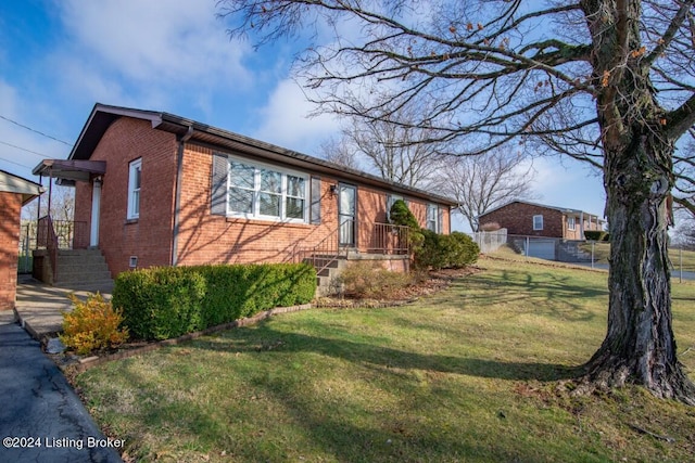 view of front facade with brick siding, a front yard, and fence