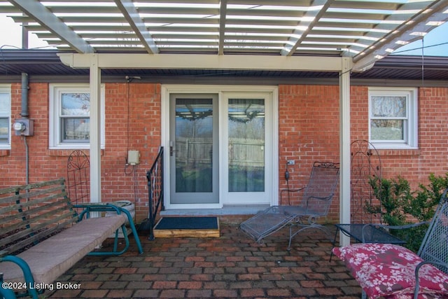 property entrance featuring a pergola and brick siding