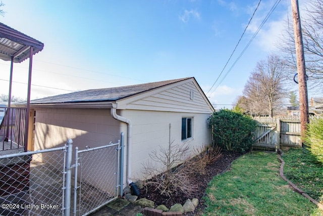 view of property exterior featuring concrete block siding, fence, roof with shingles, and a gate