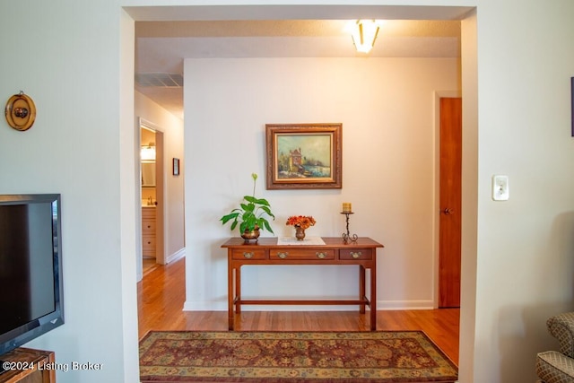 hall featuring visible vents, wood finished floors, and baseboards