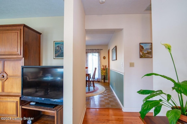 hallway with visible vents, baseboards, and wood finished floors