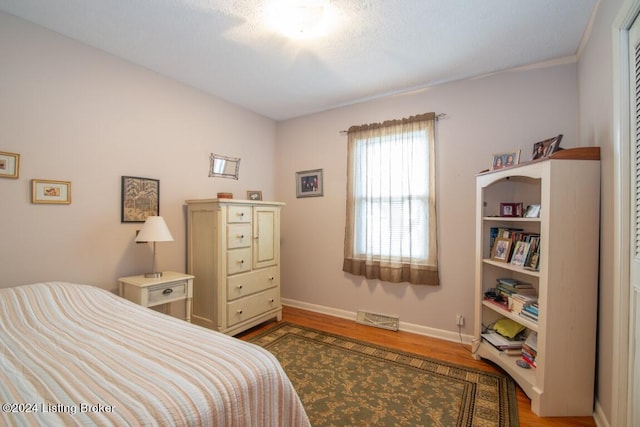 bedroom with visible vents, baseboards, and wood finished floors