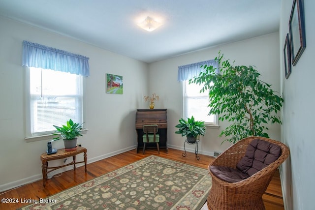 living area with a wealth of natural light, baseboards, and wood finished floors