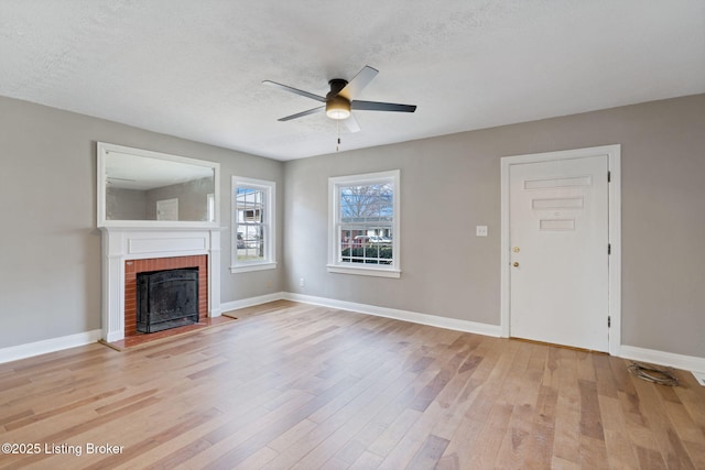 unfurnished living room with a textured ceiling, baseboards, light wood-type flooring, and a ceiling fan