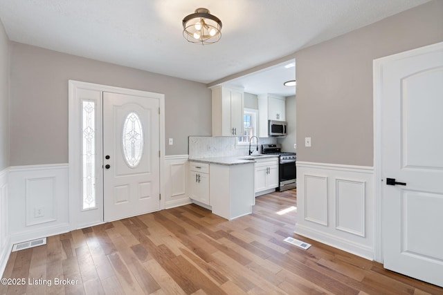 entryway featuring a wainscoted wall, light wood-style floors, and visible vents