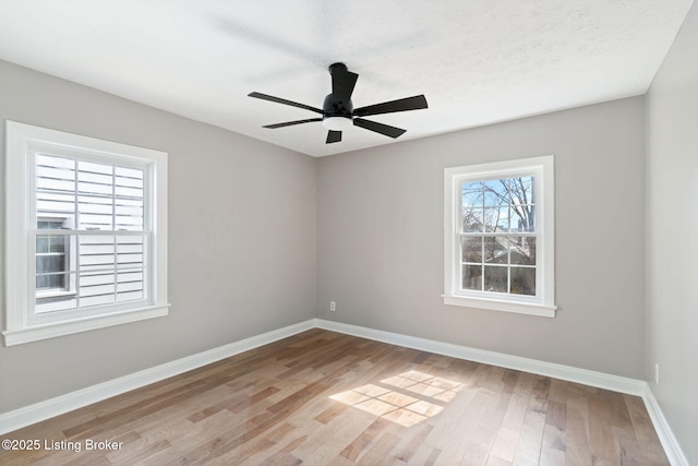 empty room featuring ceiling fan, a textured ceiling, baseboards, and wood finished floors