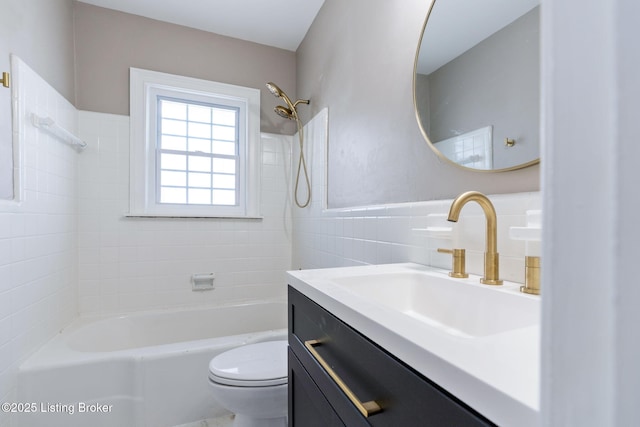 bathroom featuring toilet, vanity, tile walls, and bathing tub / shower combination