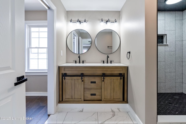 full bath with a sink, marble finish floor, double vanity, and a walk in shower