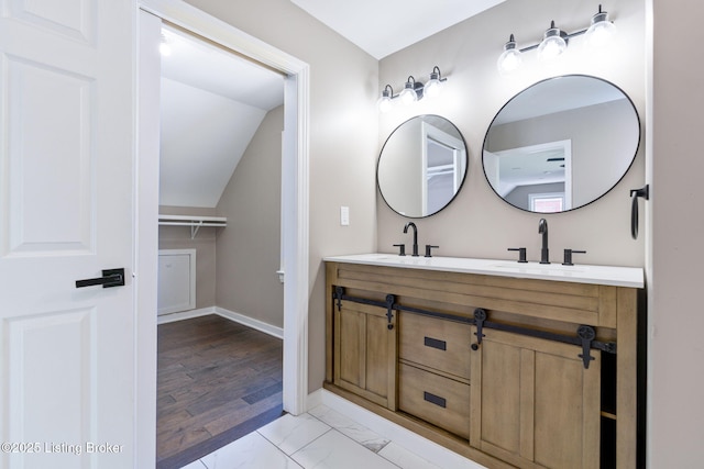 full bath featuring double vanity, marble finish floor, baseboards, and a sink